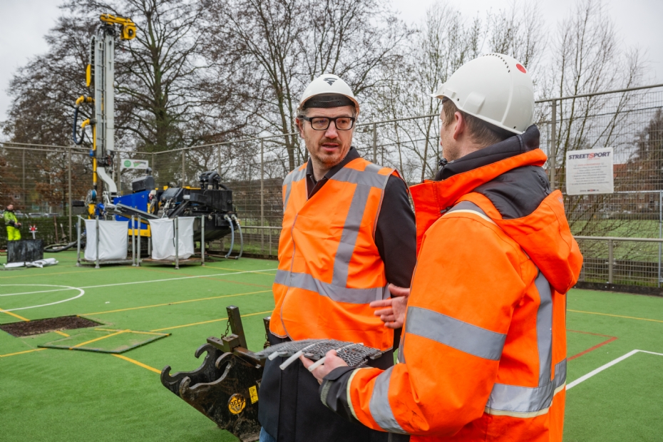 Roy Verhagen, projectleider Finovi (rechts), legt het systeem uit aan Arjen Kapteijns, wethouder Energietransitie (links), met op de achtergrond de boorinstallatie. (Foto: gemeente Den Haag)
